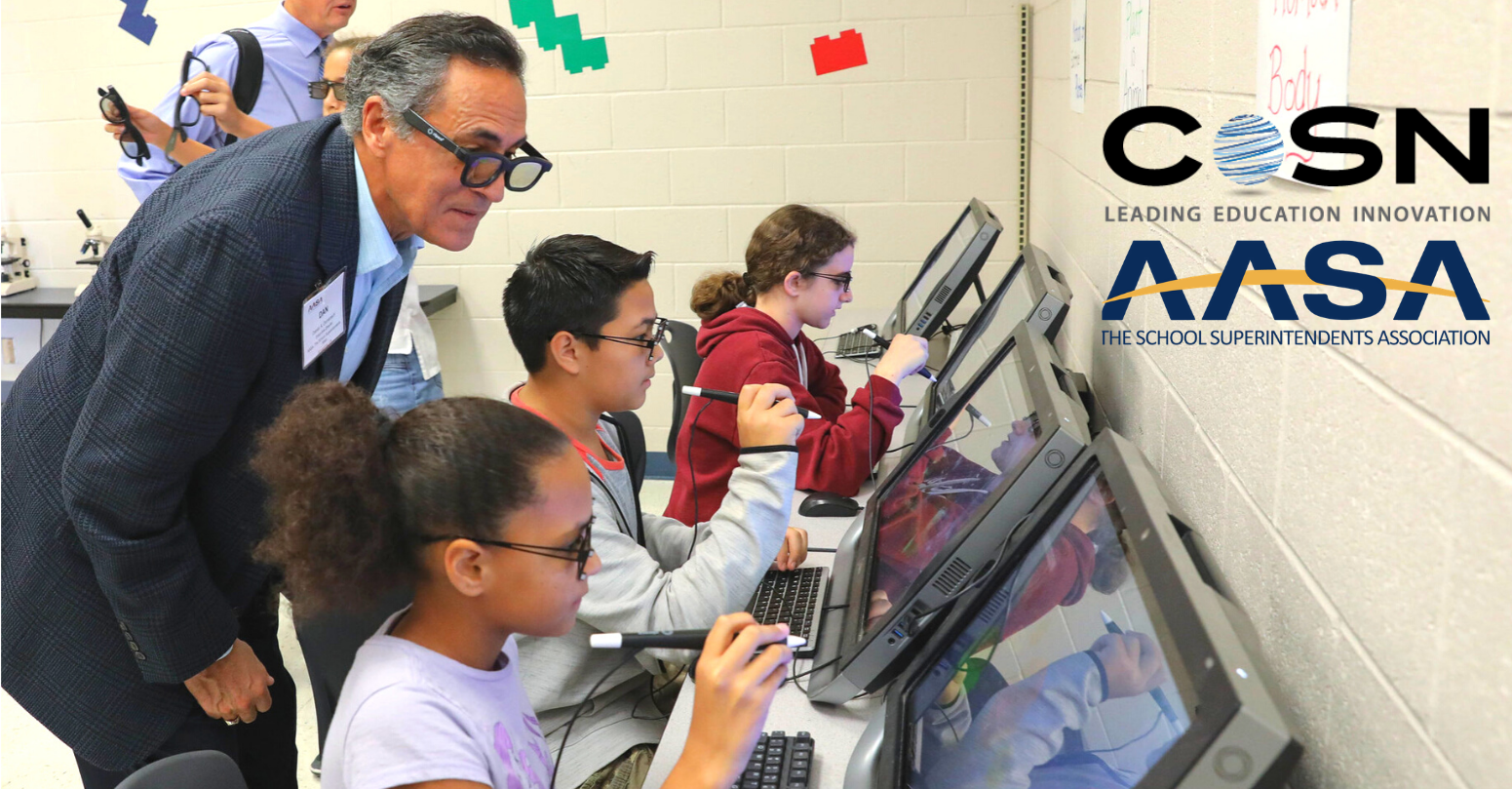 Superintendent observing school students working in front of laptops.
