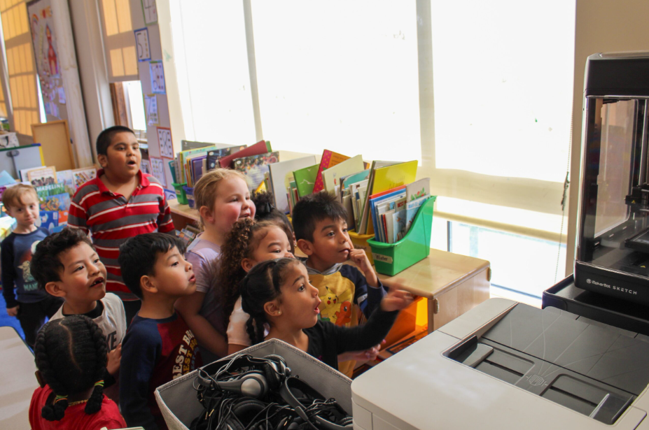 Students staring at a 3D printer working