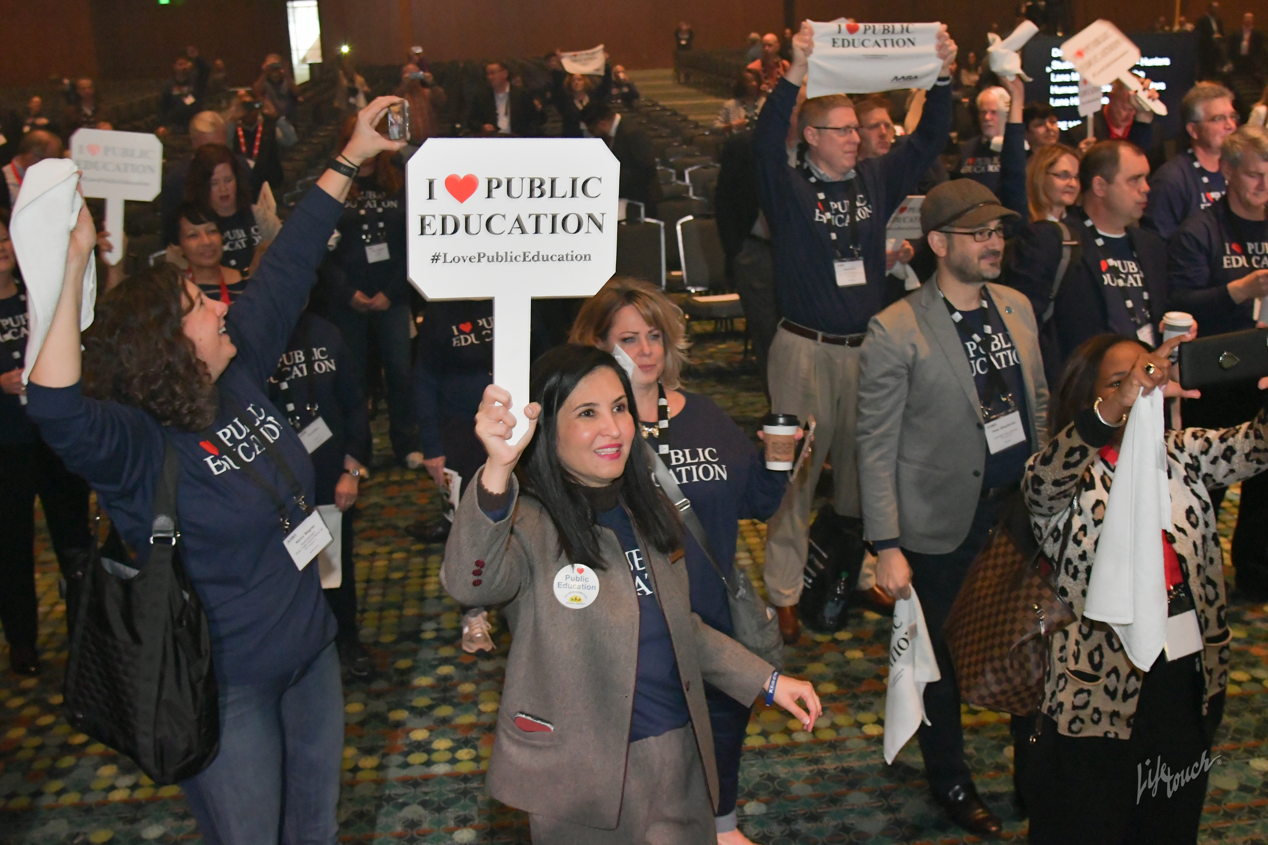 Conference attendees holding I Love Public Education signs